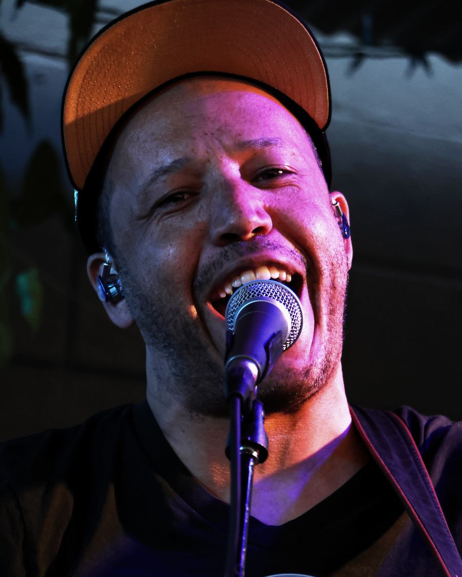Jordan Wilson at night, eyes closed, singing into the microphone.