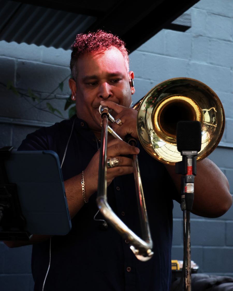 Yerfrey Fernandez playing trombone under stage lights at night.