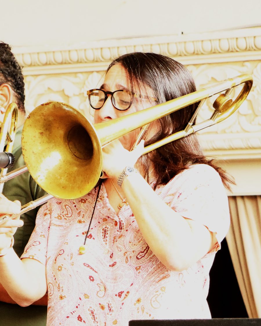 Mara Fox, in glasses and a pink paisley shirt, playing in a sunlit ballroom.